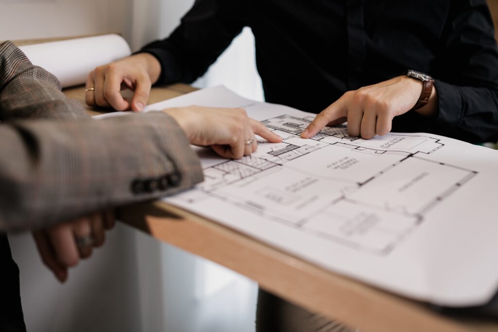 A person is pointing to a plan on top of a table.